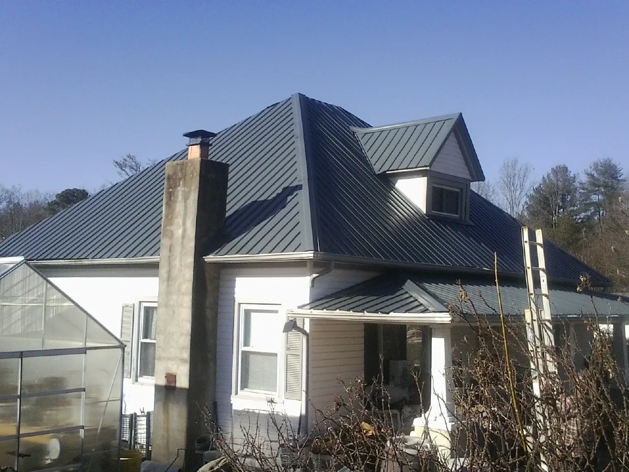 Dark blue standing seam metal roof on a white farmhouse with dormer — Slate & Tile Roof Repair by Roofing Brothers in Easton