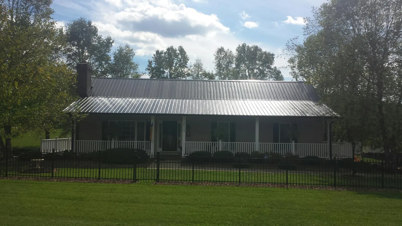 Gray metal roof on a brick ranch with a full width front porch — Gutter Guard Installation work by our crew in Easton